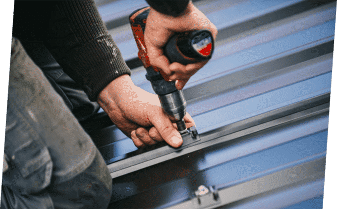 Man Inserting Screw on the Roof — Building Supplies in Heatherbrae, NSW