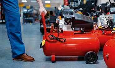 Man Pulling Air-Compressor Machine — Building Supplies in Port Stephens, NSW