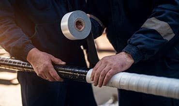 Man Putting Tapes on Metal Pipe — Building Supplies in Newcastle, NSW