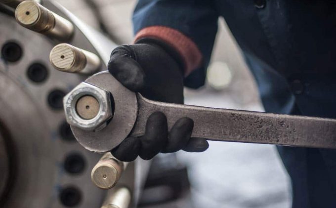 Mechanic At The Factory Screws Big Bolt With Heavy Wrench