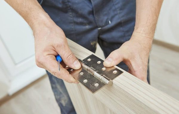 carpenter installing door hinge