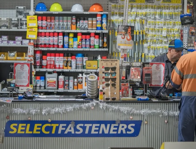 Select Fasteners counter with safety gear, sprays and hardware on the wall behind